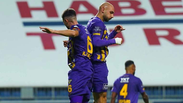 Futbolcular, sahada sevinç içinde birbirlerine sarılıyor.