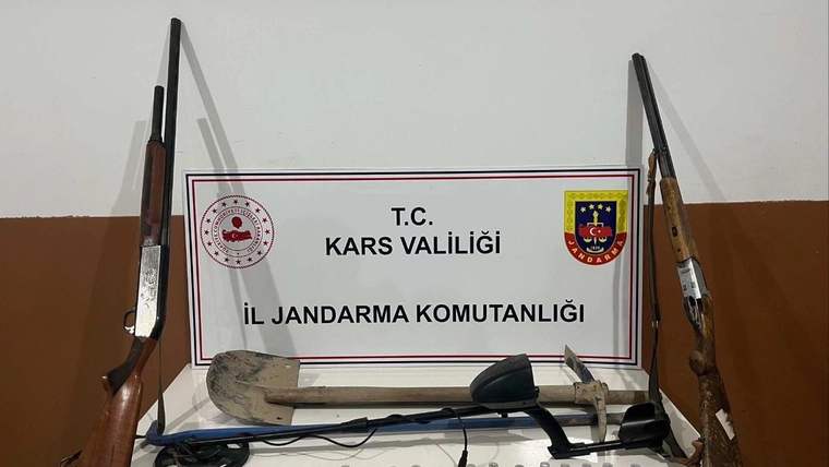 Kars Valiliği İl Jandarma Komutanlığı tabelası önünde iki tüfek, metal dedektörü ve çok sayıda fişek bulunuyor.