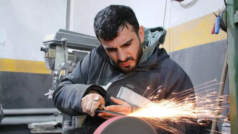 Atölyede bıçak ustası, bıçak bileme işlemi yaparken kıvılcımlar çıkıyor.