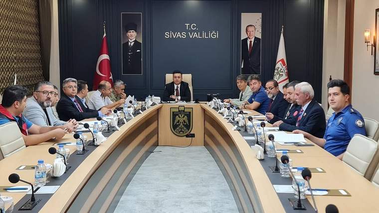 T.C. Sivas Valiliği yazılı salonda, uzun bir masa çevresinde oturan kişiler toplantı yapıyor.