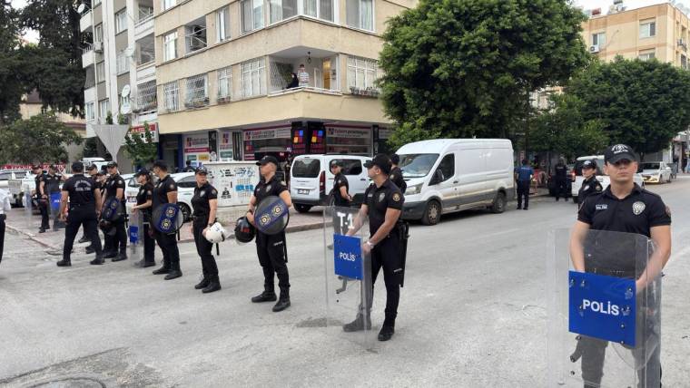 Apartman ve dükkânların önünde, kalkan taşıyan polisler cadde üzerinde sıralanıyor.