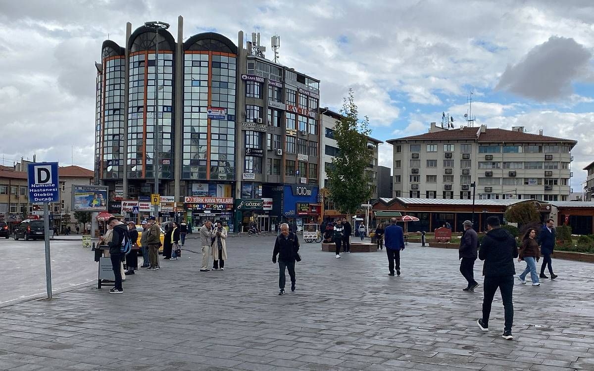 Sivas'ta bir meydanda yürüyen insanlar, arka planda modern binalar ve dükkanlar görünmekte.