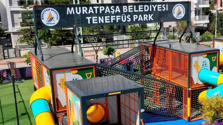 Muratpaşa Belediyesi Teneffüs Park tabelası altında, renkli tırmanma ağları ve oyun kuleleri görülüyor.