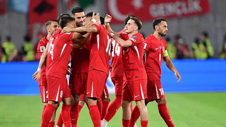 Kırmızı formalar giymiş futbolcular, gol sevinci yaşıyor.