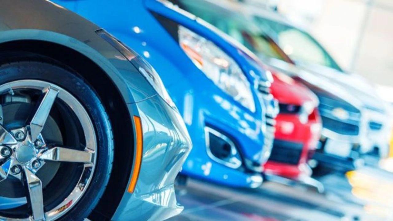 Ön planda gümüş renkli otomobil, arkasında mavi ve kırmızı renkli otomobillerin sıralandığı görülüyor.