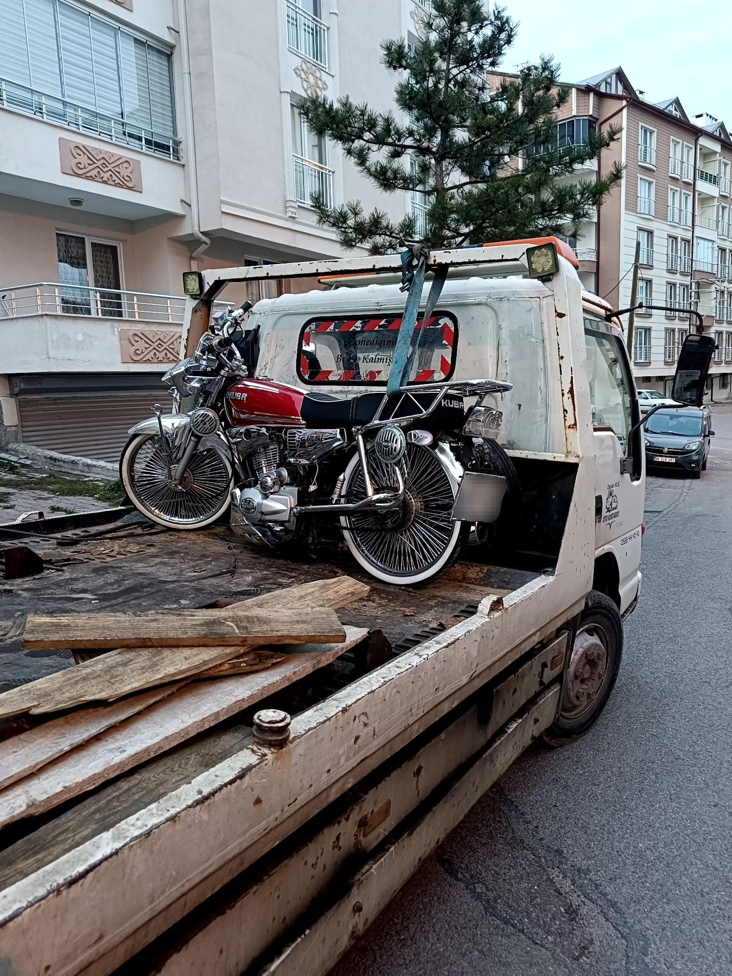Bir motosiklet, bir çekici aracın arkasında taşınıyor.