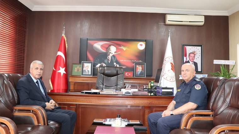 İki kişi, Sivas İl Tarım Orman Müdürlüğü'nde bir masanın etrafında oturuyor. Arka planda Türk bayrağı ve Atatürk'ün resmi var.