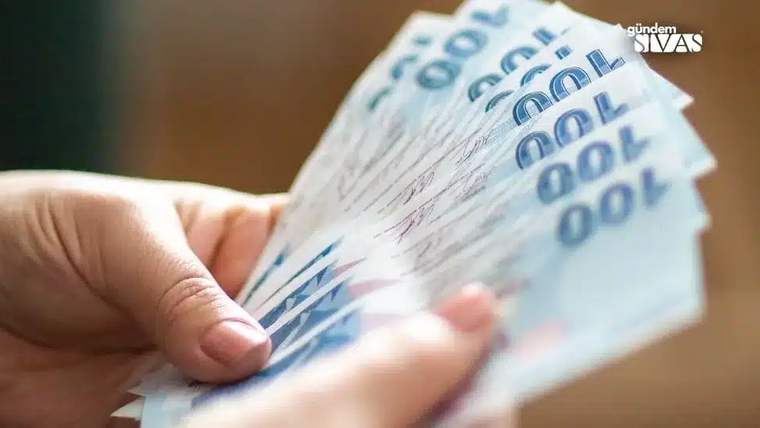 Bir kişinin elinde yüz TL banknotlarıyla dolu bir deste para bulunuyor.