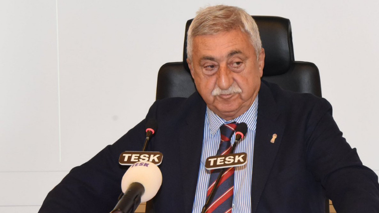 Kravatlı, bıyıklı bir kişi, önünde TESK yazılı iki mikrofonla konuşurken görüntüleniyor.