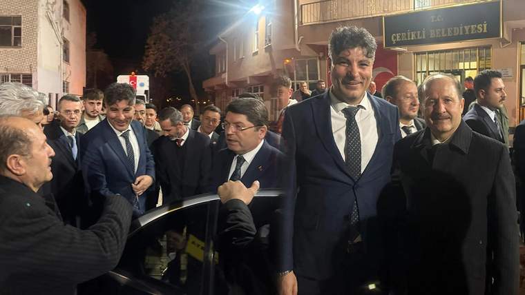 Gece, Çerikli Belediyesi tabelasının önünde takım elbiseli kişiler ve çevrelerinde toplanan kalabalık görülüyor.