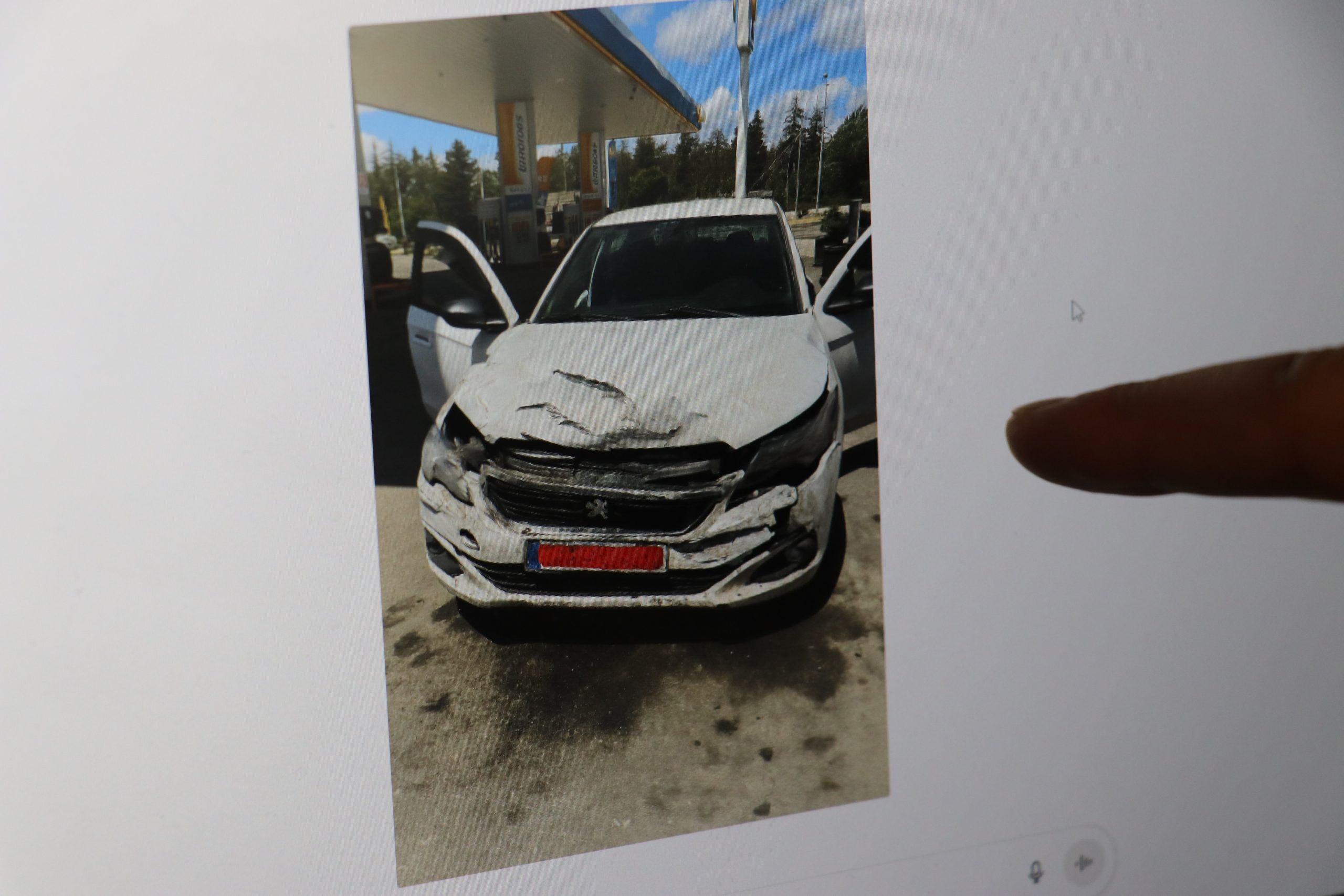 Ön kısmı hasar görmüş bir otomobil, benzin istasyonunda duruyor.