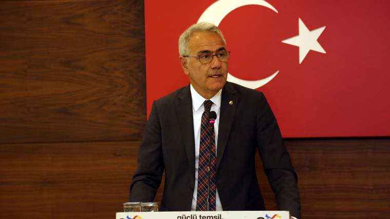 Kürsüde konuşan bir kişi, arkasında Türk bayrağı ve Sivas TSO logosu var.