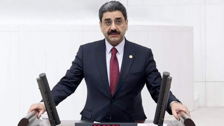 Kürsüde konuşan bir kişi, önünde mikrofonlar ve bir zamanlayıcı var.