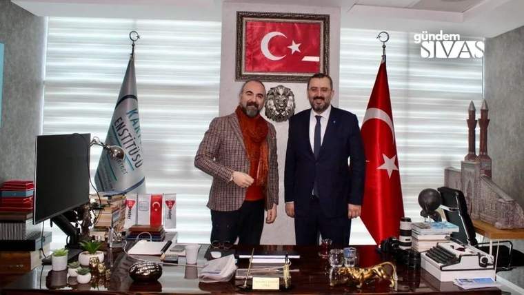 Masa arkasında yan yana duran iki erkek, Türk bayrağı ve başka bir bayrağın arasında poz veriyor.