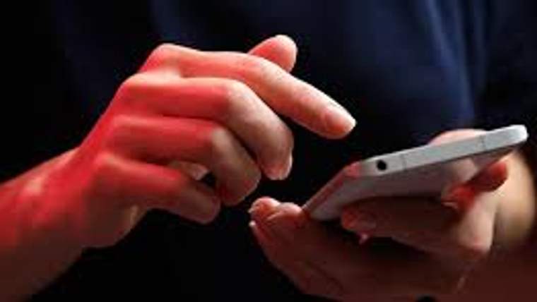 Bir kişinin akıllı telefonuna dokunduğu, parmaklarının ekranda hareket ettiği görünmektedir.