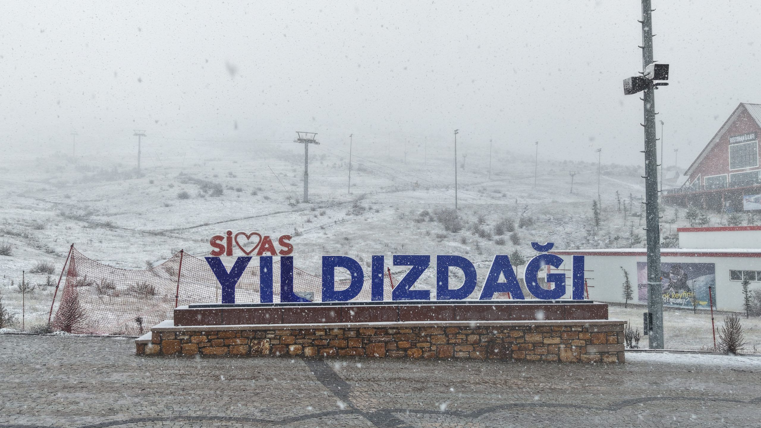 Yıldız Dağı Kayak Merkezi'nde kar yağışı altında büyük bir tabela görünmekte.