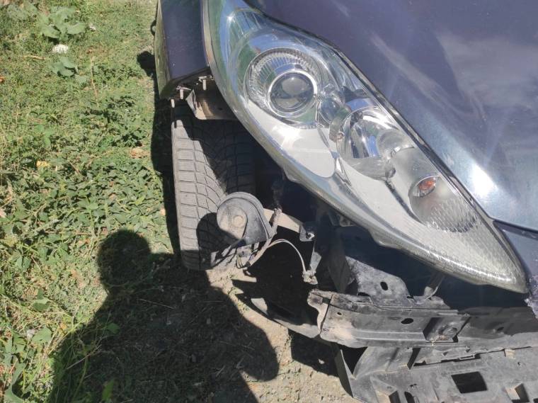 Park halindeki bir otomobilin ön kısmında hasar görünmekte, lastik ve far hasar almış.
