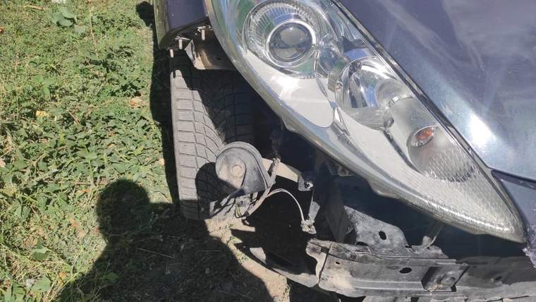 Park halindeki bir otomobilin ön kısmında hasar görünmekte, lastik ve far hasar almış.