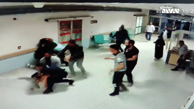 Bir grup insan hastane koridorunda kavga ediyor; bazıları yere düşmüş, diğerleri müdahale ediyor.
