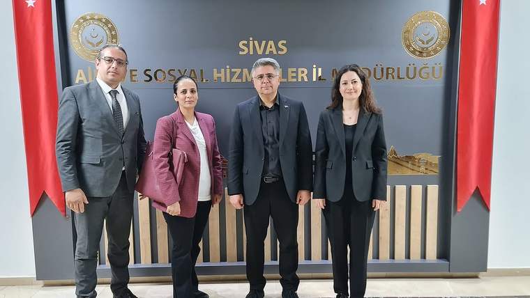 Sivas Aile ve Sosyal Hizmetler İl Müdürlüğü yazılı panonun önünde dört kişi ve iki Türk bayrağı duruyor.
