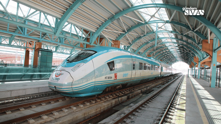 Mavi-beyaz renkte bir Yüksek Hızlı Tren, raylar üzerinde duruyor.