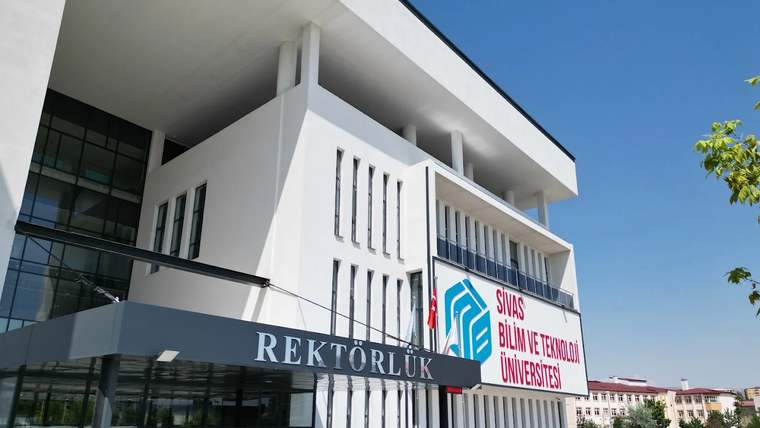 Sivas Bilim ve Teknoloji Üniversitesi Rektörlük binasının giriş cephesi ve önündeki taş döşeli alan görülüyor.