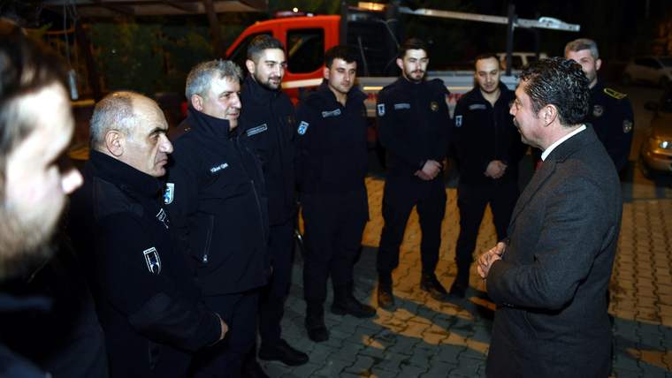 Bir grup güvenlik personeli, bir adamın önünde duruyor ve onu dinliyor.