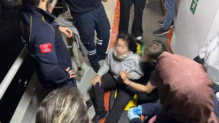 Yaralı bir kişi, yolcu motorunda sağlık ekipleri tarafından tedavi ediliyor.