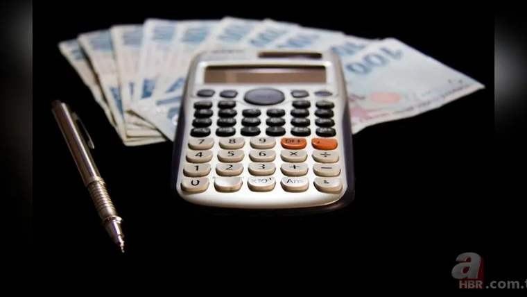 Türk lirası banknotları ve bir kalem yanında, siyah zeminde elektronik hesap makinesi duruyor.