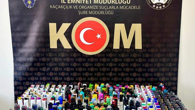 Üzerinde Sivas Valiliği ve KOM yazıları bulunan pano önünde, çok sayıda renkli kutu ve şişe sergileniyor.