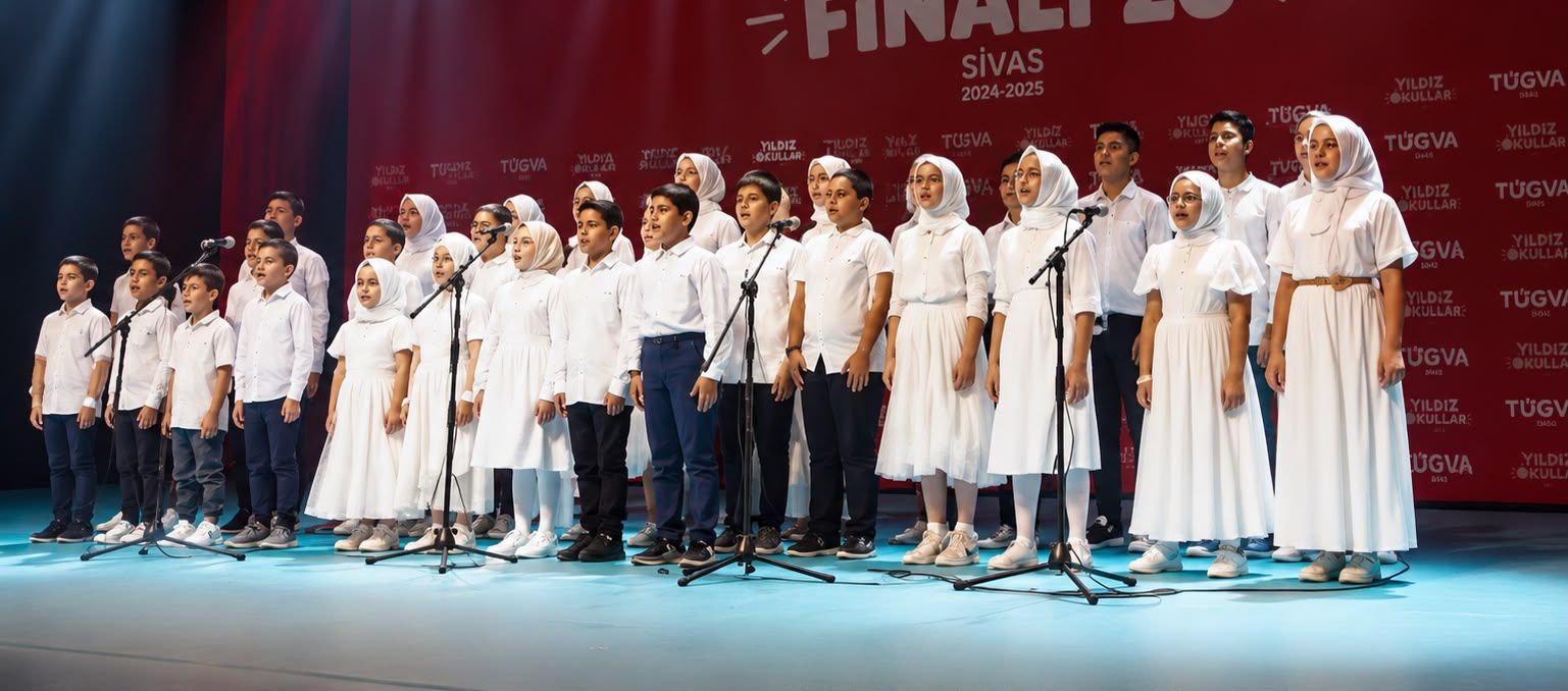 Beyaz kıyafetli çocuk ve gençler, mikrofonların önünde sahnede sıra halinde duruyor; arkada Sivas yazısı görülüyor.