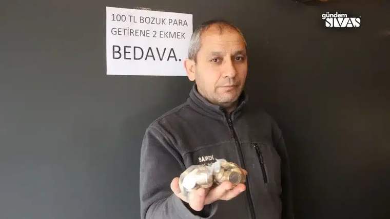Elinde bozuk paralar tutan bir kişi, arkasındaki tabelada “100 TL bozuk para getirene 2 ekmek bedava” yazıyor.