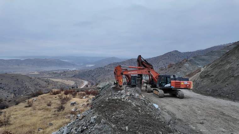 Bir inşaat alanında, toprak kayması sonrası kurtarma çalışmaları için bekleyen bir ekskavatör.