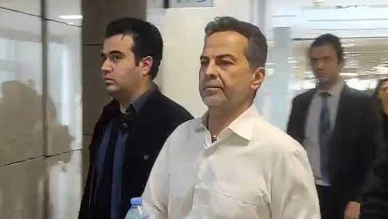 Bir kişi, yanında başka bir kişi ile birlikte bir koridorda yürüyor.