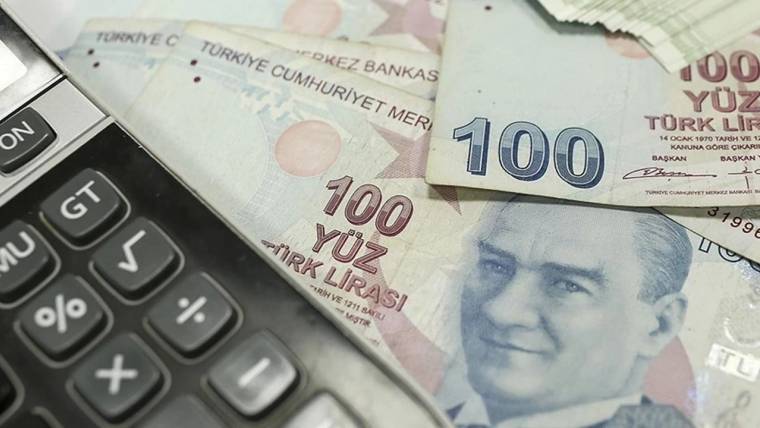 Üzerinde Atatürk resmi bulunan 100 TL banknotlar ve bir hesap makinesi.