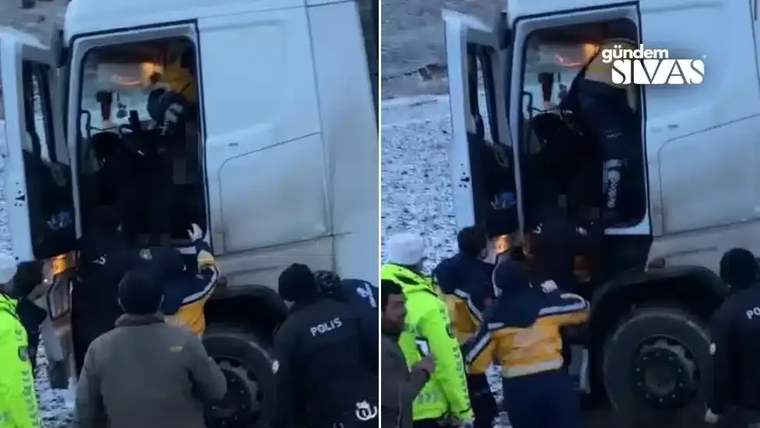 Bir tırın kabin çevresinde, polis ve sarı yelekli görevliler bir kişiye yardım ediyor.