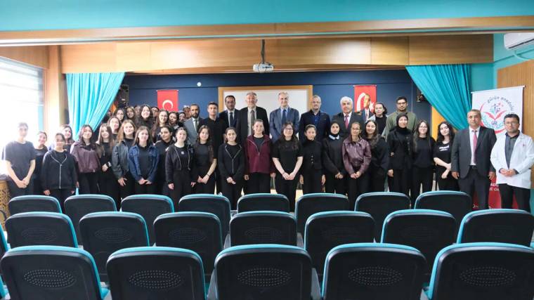 Bir grup bilim insanı ve öğrencinin bir arada poz verdiği etkinlik alanı, arka planda Türk bayrakları var.