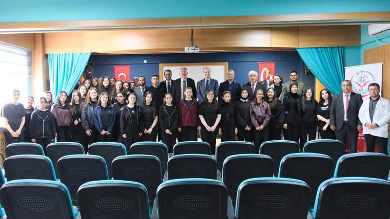 Bir grup bilim insanı ve öğrencinin bir arada poz verdiği etkinlik alanı, arka planda Türk bayrakları var.