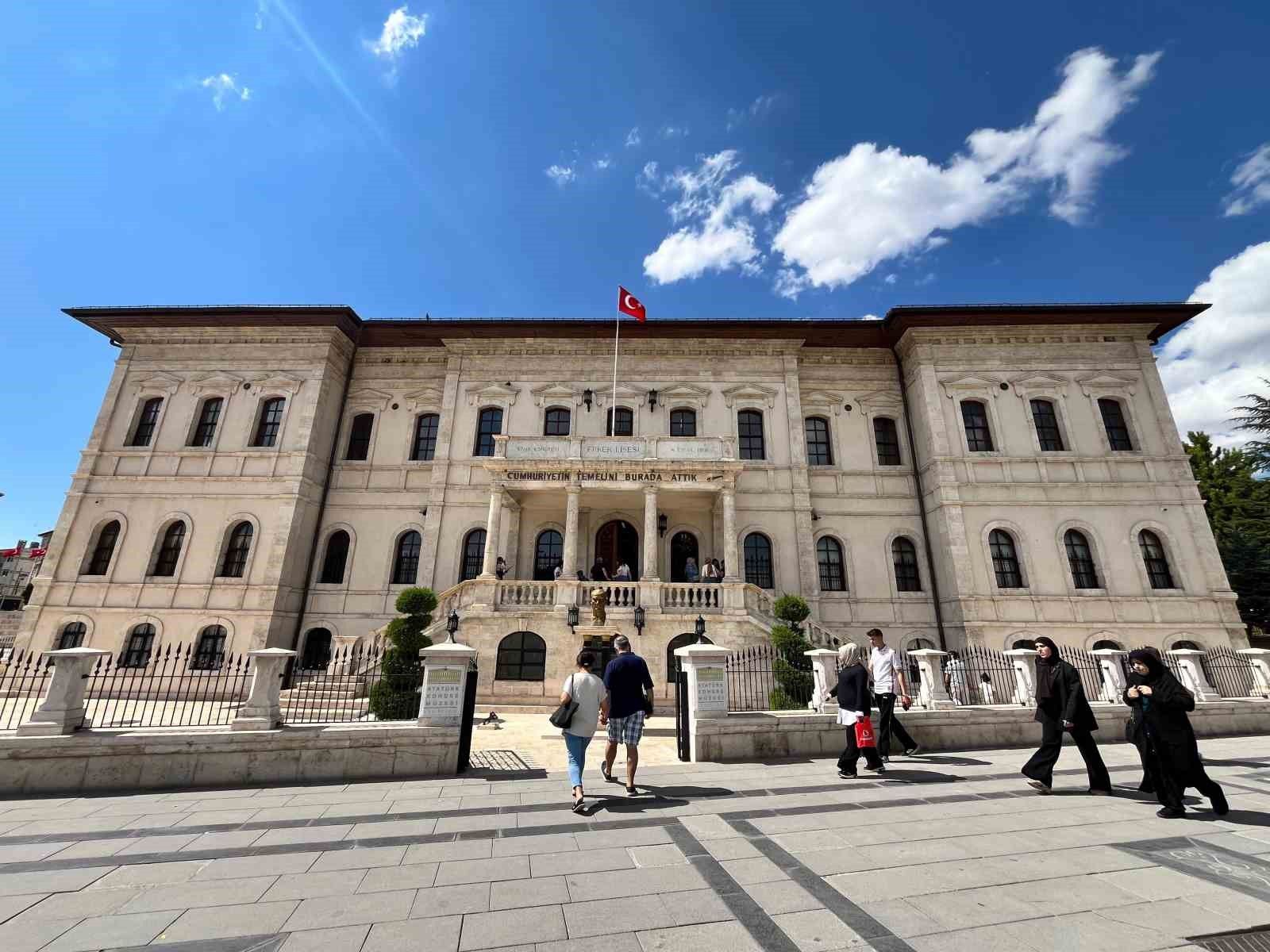 Taş cepheli tarihi müze binasının önünde Türk bayrağı ve yürüyen ziyaretçiler görülüyor.