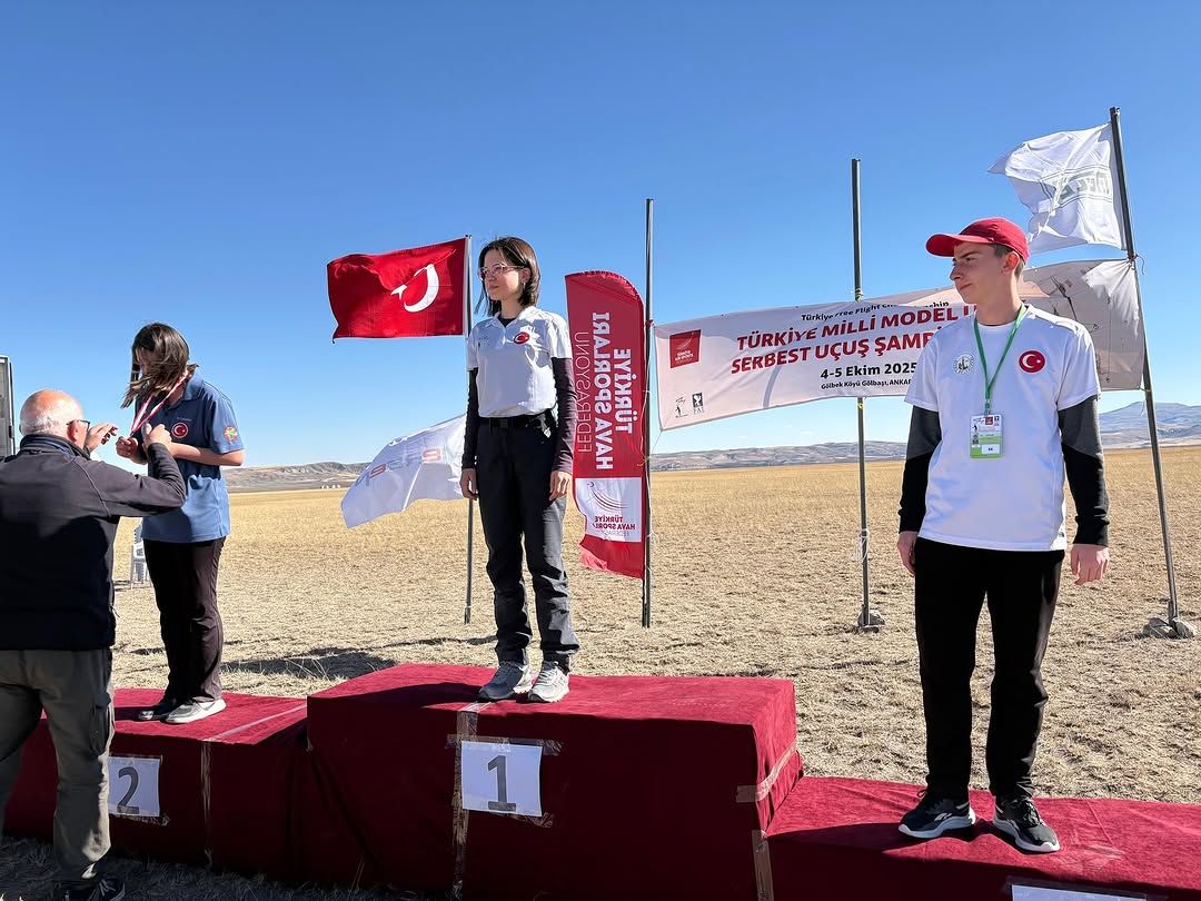 Üzerinde Türk bayrağı bulunan podyumda, genç sporcular madalya alıyor.