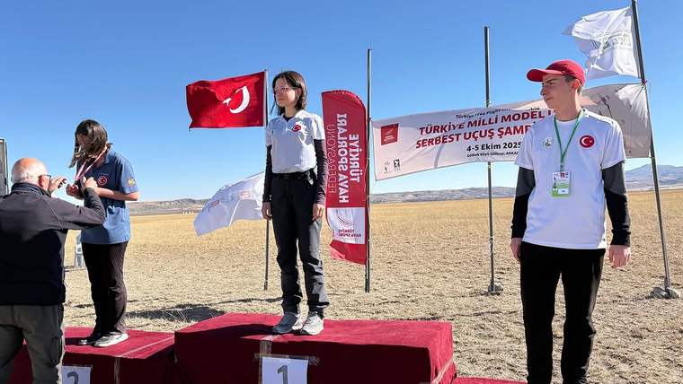 Üzerinde Türk bayrağı bulunan podyumda, genç sporcular madalya alıyor.