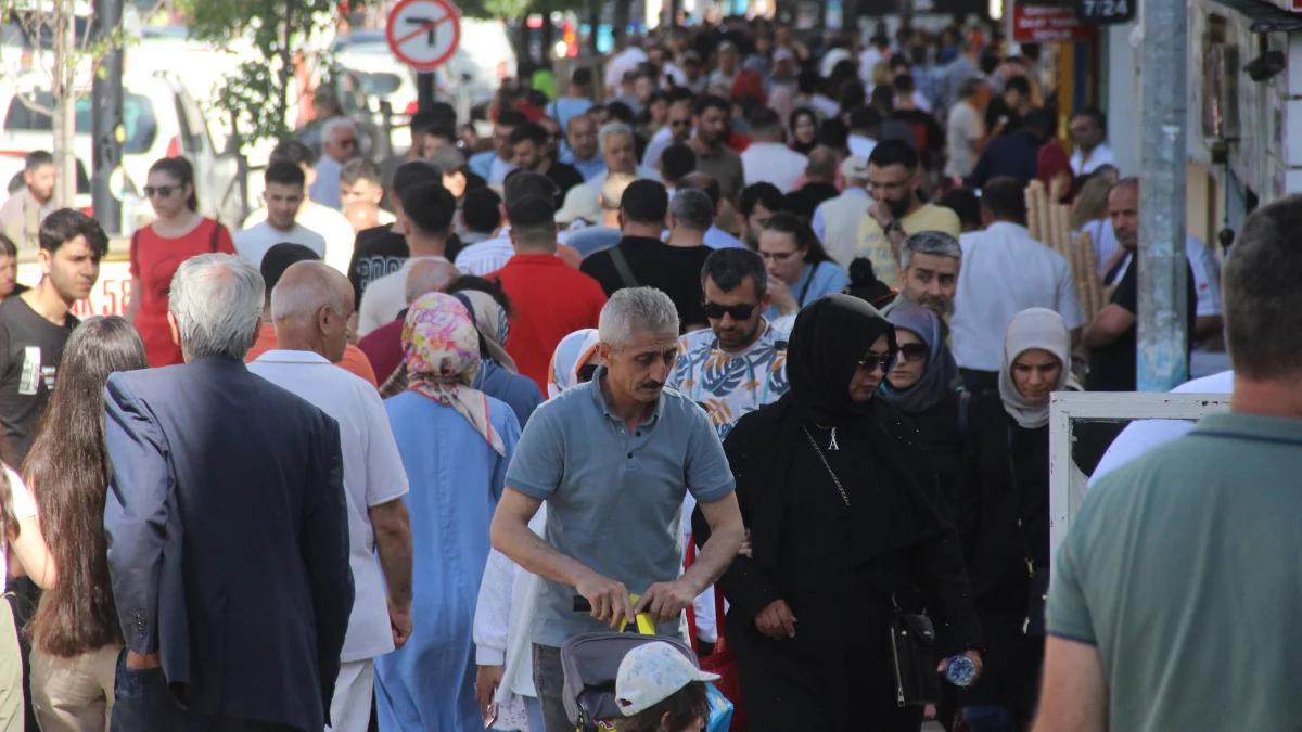 Yoğun bir caddede yürüyen kalabalık, çeşitli giyim tarzlarıyla dikkat çekiyor.