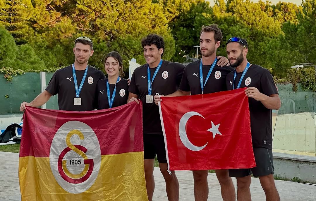 Galatasaray sporcuları, madalya ve bayraklarla birlikte poz veriyor.