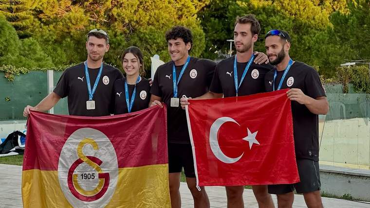 Galatasaray sporcuları, madalya ve bayraklarla birlikte poz veriyor.