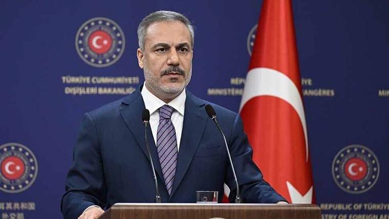 Kürsüde konuşan bir kişi, arkasında Türk bayrağı ve Türkiye Cumhuriyeti Dışişleri Bakanlığı logosu var.