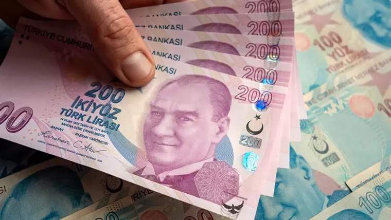 Bir kişinin elinde 200 Türk liralık banknotlar tutuluyor, arka planda başka banknotlar görünmekte.