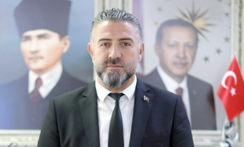 Fatih Deveci, arkasında Atatürk ve Erdoğan'ın portreleriyle birlikte, resmi bir kıyafetle poz veriyor.