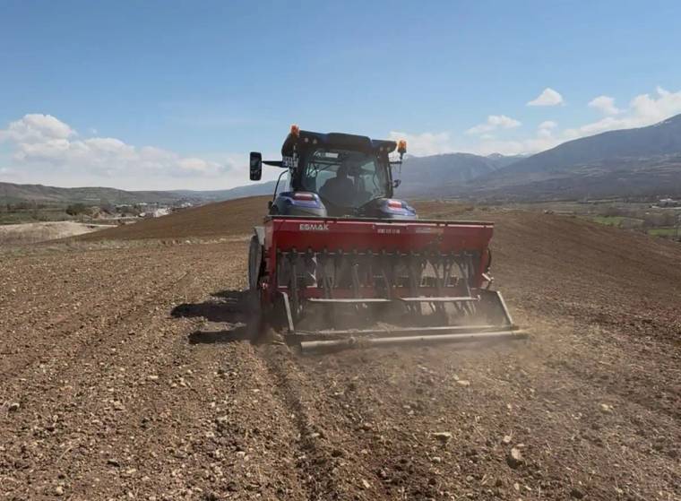 Tarla üzerinde nohut ekimi yapan bir traktör, toprakta izler bırakıyor.