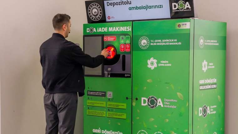 Bir kişi, depozito iade makinesine ambalajını yerleştiriyor.