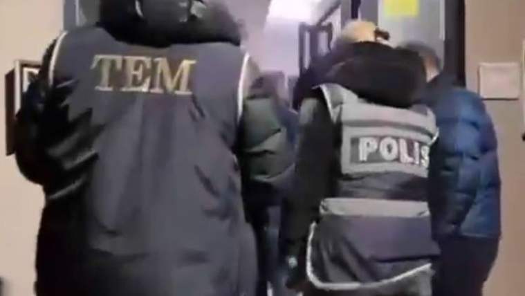 Üzerinde “TEM” ve “POLİS” yazılı yelekler bulunan iki görevli, bir kişiyi bina koridorunda yürütüyor.